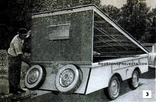 A man raising the rear wall panel of a folding hardsided trailer.